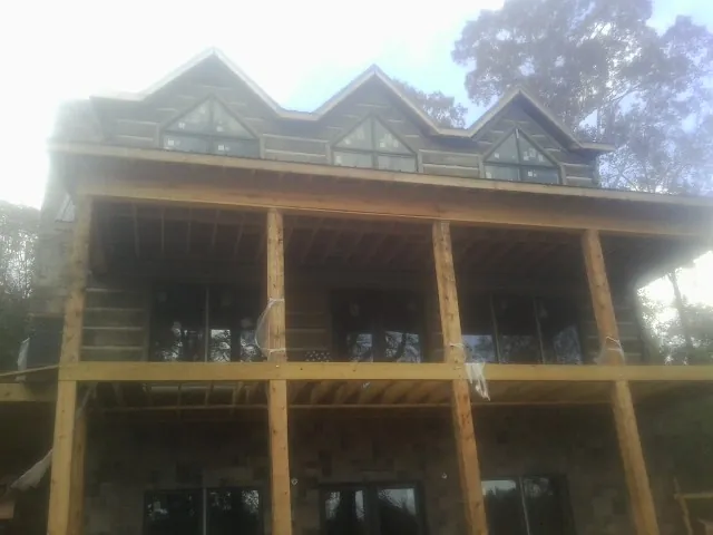Dormers and porch framing on a large log home under construction — Roof Coating work by our crew in Commerce